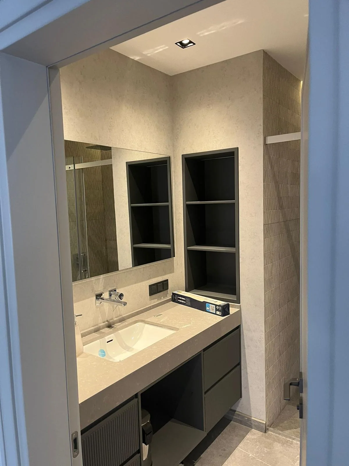 Tamamlanmış lavabo duvarı; gömme nişler ve ayna aydınlatması yerleşmiş hâlde.